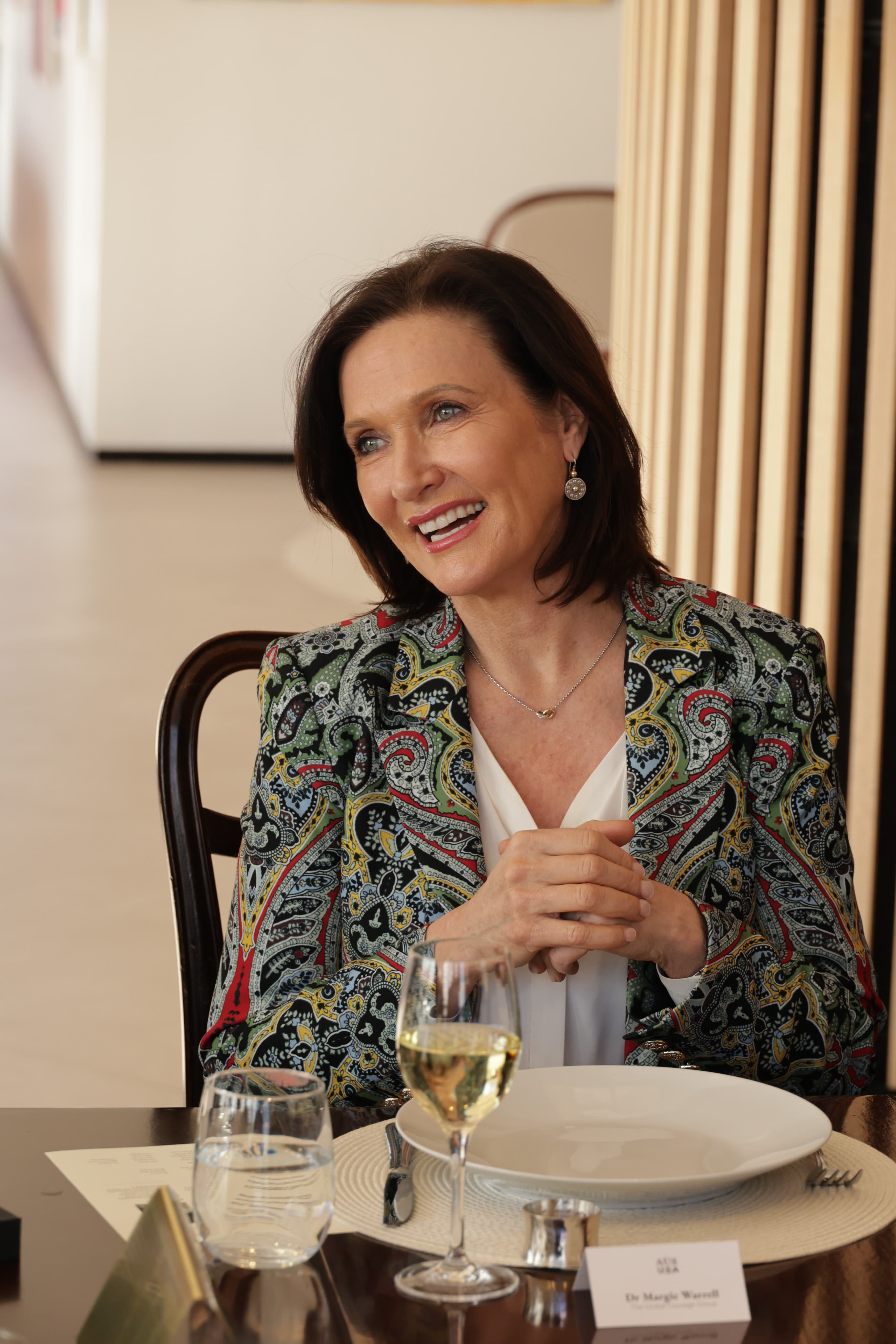 Margie Warrell seated in a floral jacket during an interview in a wood-panelled room